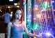 A woman blowing a bubble gum in front of a wall of lights.