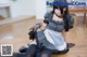 A woman in a maid outfit sitting on the floor.