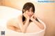 A naked woman sitting in a bathtub with her hand on her chin.