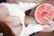 A woman eating a slice of watermelon with a spoon.