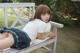 A young woman sitting on a wooden bench in a park.