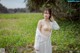 A woman in a white dress standing in a field.