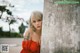 A woman in a red dress leaning against a wall.