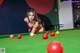 A woman in a red bikini playing pool.